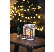 Căsuță decorativă din turtă dulce cu zăpadă și brad de Crăciun în fundal