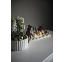 Scenă decorativă de Crăciun cu case, copaci și sania lui Moș Crăciun