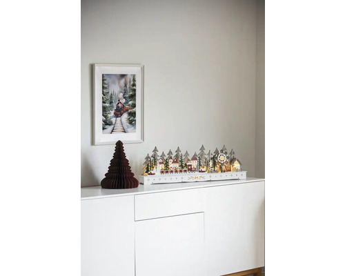 Sat decorativ de Crăciun cu tren pe o comodă albă, cu o imagine a unui tren pe perete.