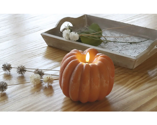 Lumânare decorativă de dovleac cu tavă și accente florale pe o masă de lemn