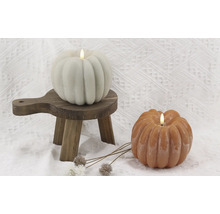 Două lumânări dovleac cu lumini LED pe un mic taburet din lemn