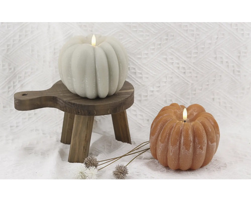 Două lumânări dovleac cu lumini LED pe un mic taburet din lemn