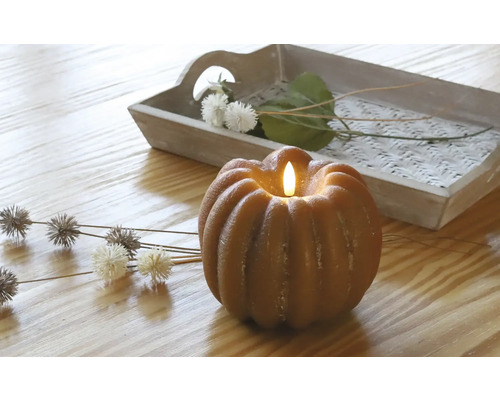 Lumânare decorativă de dovleac cu lumină LED pe o masă cu tavă de lemn