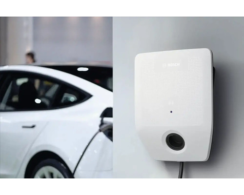 Stație de încărcare albă pentru mașini electrice lângă o mașină albă