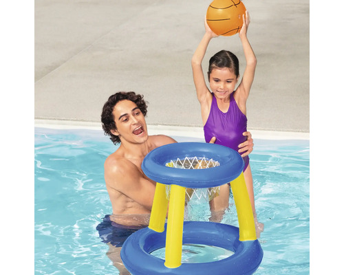 Tată și fiică se joacă cu un coș de baschet gonflabil în piscină.