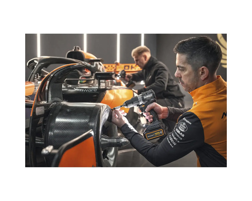 Un bărbat folosește o șurubelniță electrică DeWalt pe o mașină de curse.