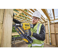 Artizan folosind un pistol de bătut cuie cu acumulator DeWalt pe un șantier