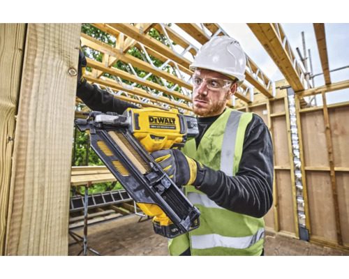 Artizan folosind un pistol de bătut cuie cu acumulator DeWalt pe un șantier