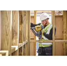 Un muncitor în construcții folosește un capsator DeWalt pe un șantier