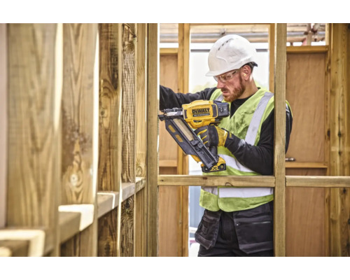 Un muncitor în construcții folosește un capsator DeWalt pe un șantier