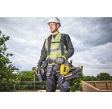 Un muncitor în construcții cu cască de protecție, vestă de siguranță, ochelari de protecție și curea pentru scule poartă un aparat de bătut cuie DeWalt.