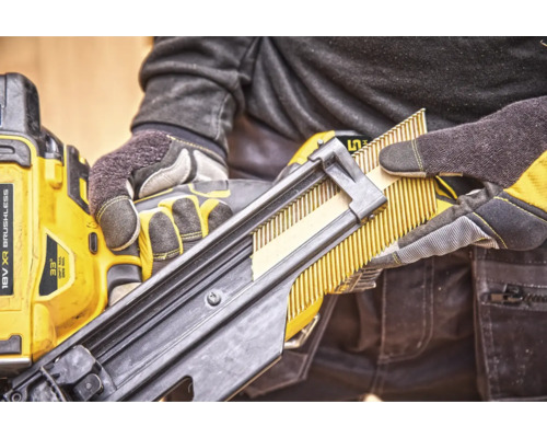 Un muncitor încarcă un pistol de bătut cuie cu cuie în bandă.