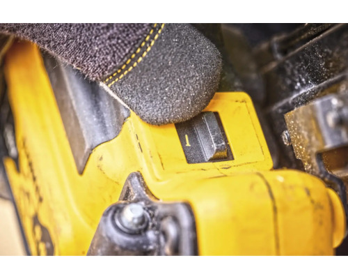 Prim-plan al unei scule galbene cu un comutator acționat de un deget înmănușat