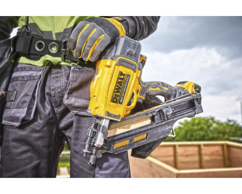 O persoană cu mănuși de lucru și curea de scule poartă un aparat de bătut cuie DeWalt galben.