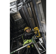 Un muncitor în construcții fixează material izolator pe un perete cu ajutorul unui pistol de bătut cuie cu acumulator DeWalt.