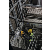 Un muncitor în construcții fixează o șină metalică de un perete cu un pistol de împușcat cu șuruburi.