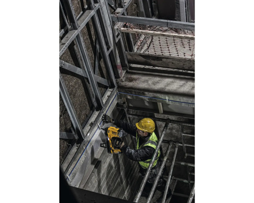 Un muncitor în construcții fixează o șină metalică de un perete cu un pistol de împușcat cu șuruburi.