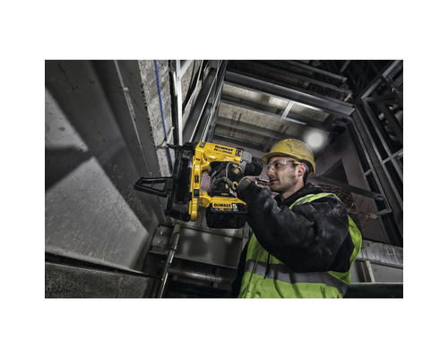 Un muncitor în construcții folosește un aparat de bătut cuie fără fir DeWalt pe un șantier.