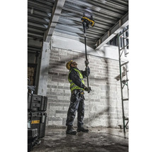 Un muncitor în construcții operează un instrument DeWalt pentru a fixa cabluri de un tavan.