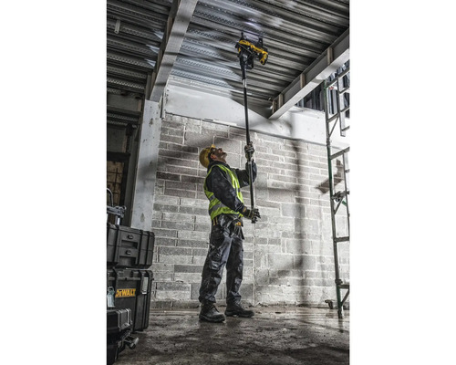 Un muncitor în construcții operează un instrument DeWalt pentru a fixa cabluri de un tavan.