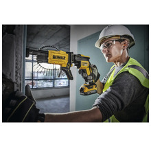 O persoană folosește o șurubelniță cu magazie galbenă DeWalt cu acumulator pentru a înșuruba un șurub într-un perete.