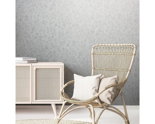 Atmosferă decorativă de locuit cu tapet cu model floral, fotoliu de ratan și comodă din lemn