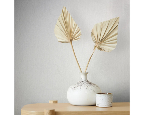 Frunze decorative de palmier uscate într-o vază albă pe o masă