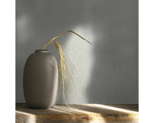 Tapet decorativ cu model textil și vază cu spic de grâu pe o masă de lemn.