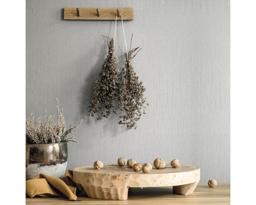 Scenă decorativă cu elemente din lemn, ierburi și nuci pe un perete texturat