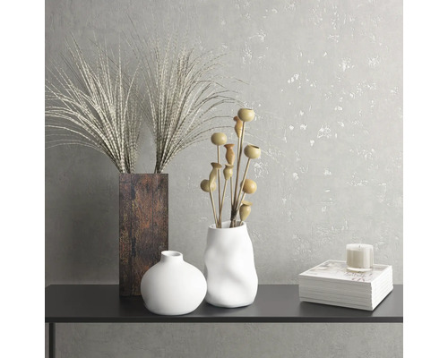 Natură statică decorativă cu vaze, plante ornamentale, lumânare și carte pe o masă.