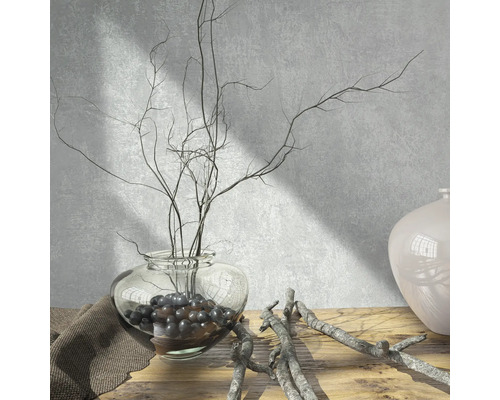 Scenă decorativă cu o vază de sticlă, crengi și bile decorative pe o masă de lemn.