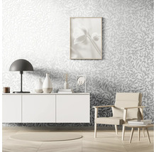 Living cu tapetă în relief, comodă, lampă, fotoliu și articole decorative.