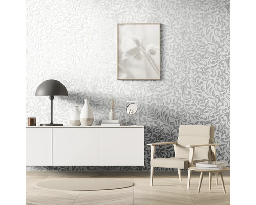 Living cu tapetă în relief, comodă, lampă, fotoliu și articole decorative.