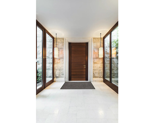 Zonă de intrare cu ușă din lemn, covoraș de intrare, perete de piatră și lămpi suspendate