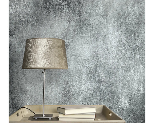 Prim-plan cu tapet de perete cu model abstract lângă o lampă și cărți.