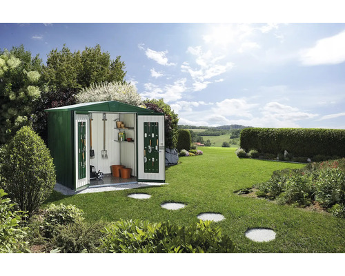 Căsuță de grădină din metal cu uși deschise și unelte de grădinărit într-un spațiu exterior verde