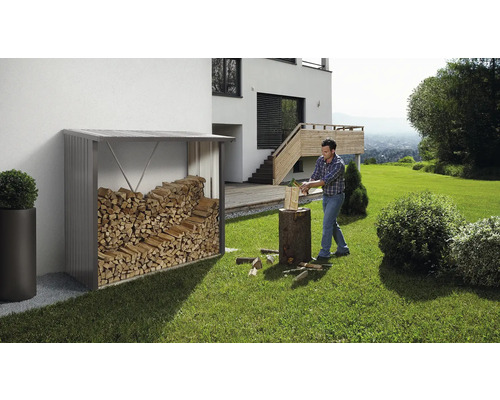 Raft de depozitare a lemnului de foc în grădină cu un bărbat care taie lemne