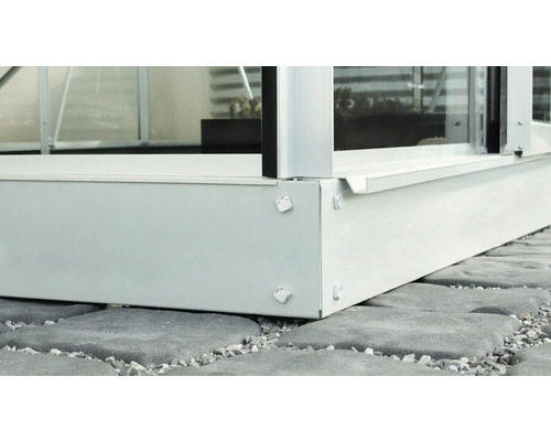 Imagine detaliată cu fundația metalică a unei sere pe pietre de pavaj.