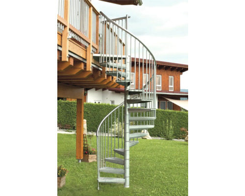 O scară spiralată metalică duce de pe o terasă într-o grădină.