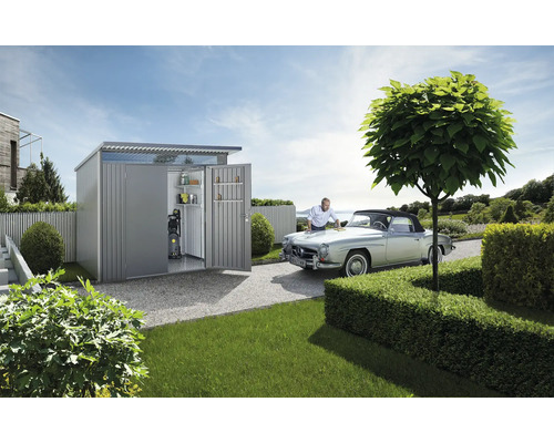 Scenă de grădină cu magazie de grădină, mașină de epocă și bărbat care are grijă de mașină