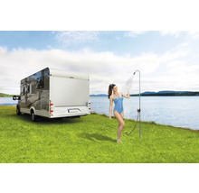 Femeie sub duș de camping lângă rulotă pe gazon lângă lac