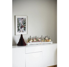 Scenă decorativă de Crăciun cu peisaj de iarnă iluminat, brad de hârtie și imagine cu tren pe un dulap alb