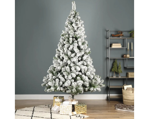 Brad împodobit, cu zăpadă, cu cadouri în sufragerie.