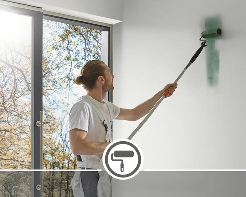 O persoană zugrăvește un perete cu o rolă de vopsea și un mâner telescopic.