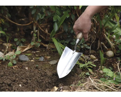Grădinar plantând cu o plantatoare în grădină.