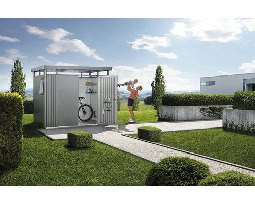 Scenă de grădină cu magazie de scule, bicicletă, rafturi și o femeie care ridică un copil