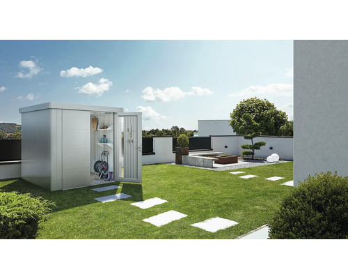 Grădină cu magazie metalică, ușă deschisă și unelte de grădinărit