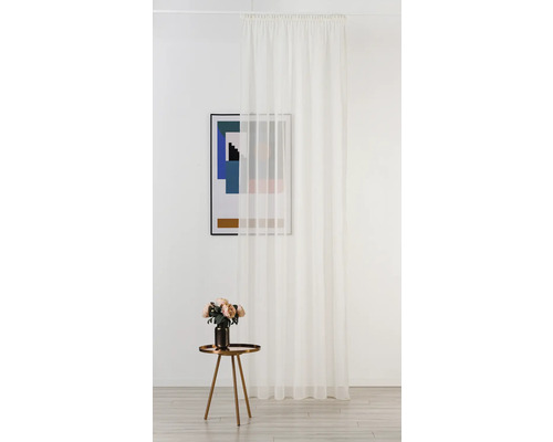 Cameră decorativă cu perdea albă transparentă, măsuță laterală cu flori și o imagine înrămată.