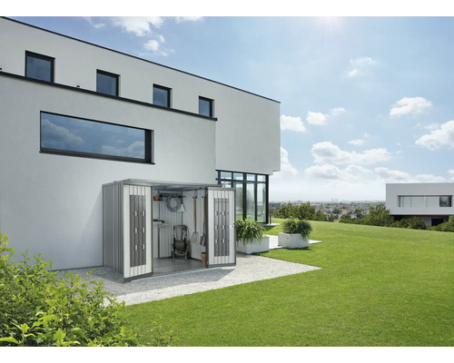Scenă de grădină cu o magazie de scule metalică sprijinită de un perete al casei