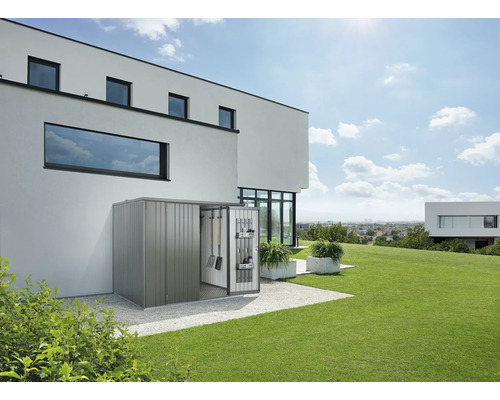 Magazie metalică pentru scule cu ușa deschisă și unelte de grădină într-o grădină modernă